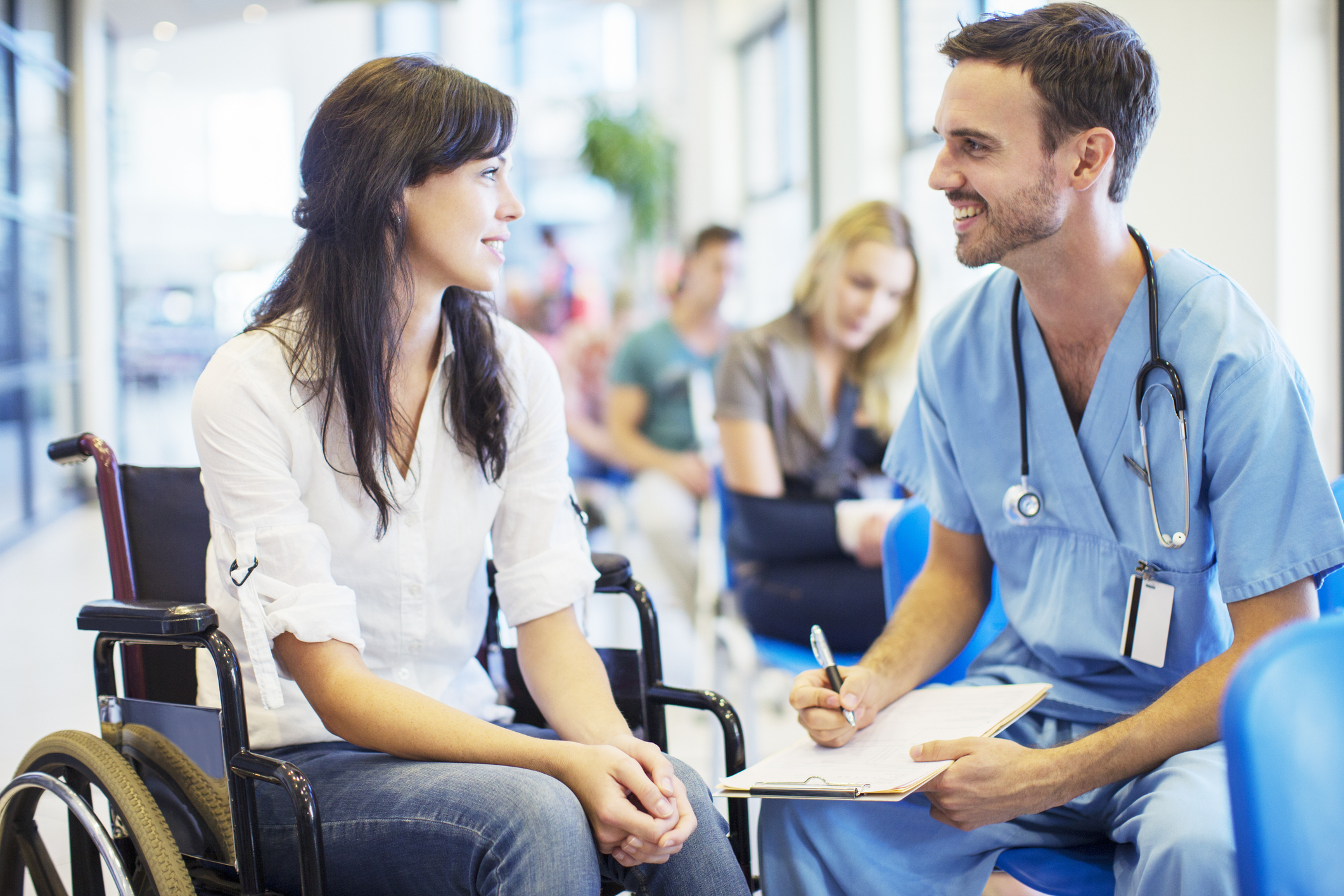 A woman in a wheelchair converses with a man, both engaged in a friendly discussion.