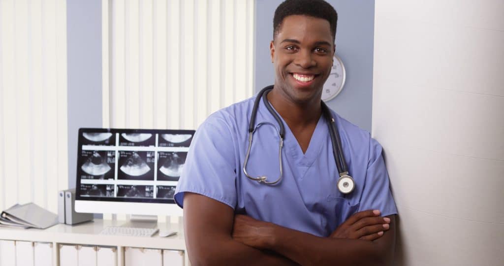A male medical assistant smiling at work