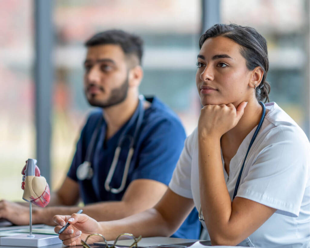 Two nurses listening to career training in classroom