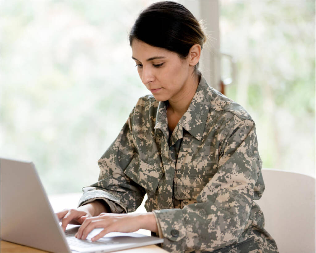 Military personnel in uniform working on laptop