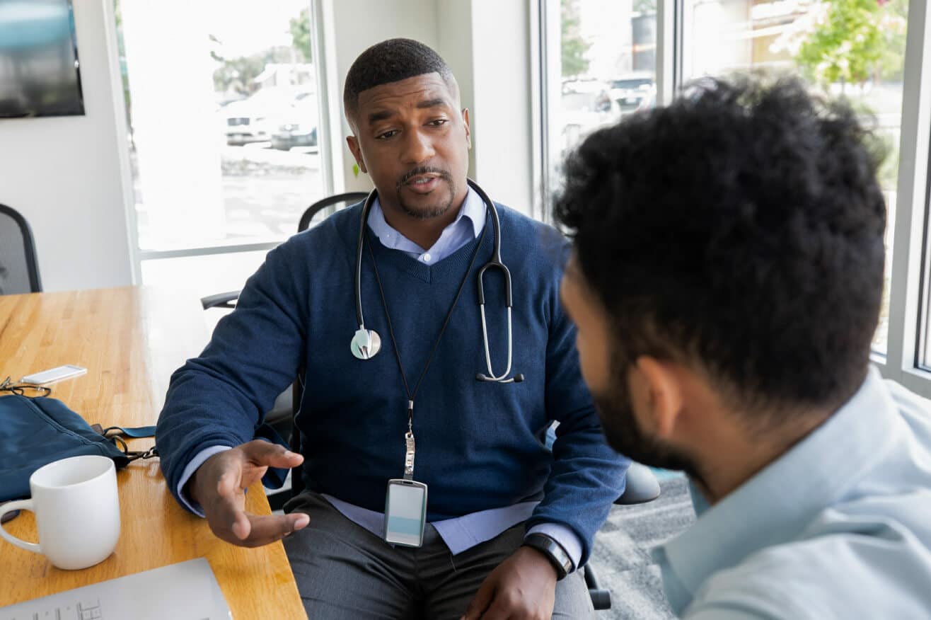 A man engages in conversation with a doctor, seeking medical advice in a clinical environment.