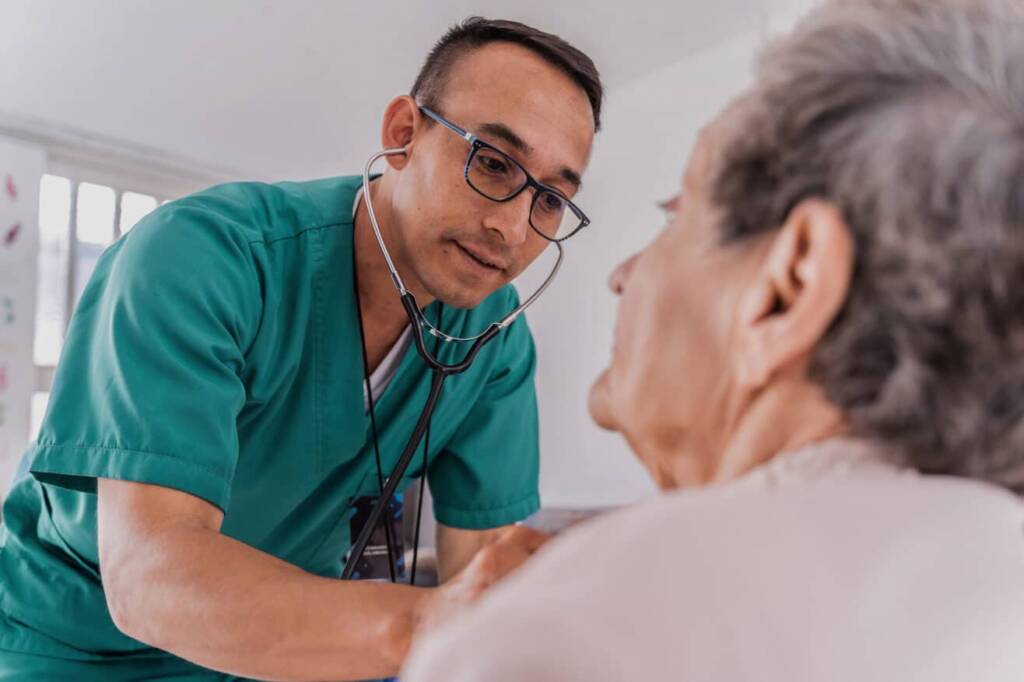 man in green scrubs helping an older women