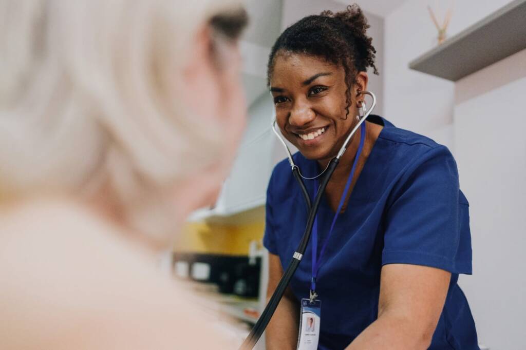 A nurse smiles warmly at a patient, creating a comforting and supportive atmosphere in a healthcare setting.