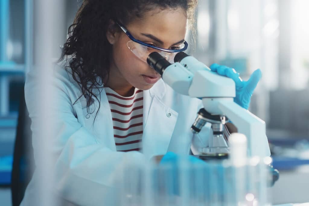 Woman reviewing specimen in a microscope