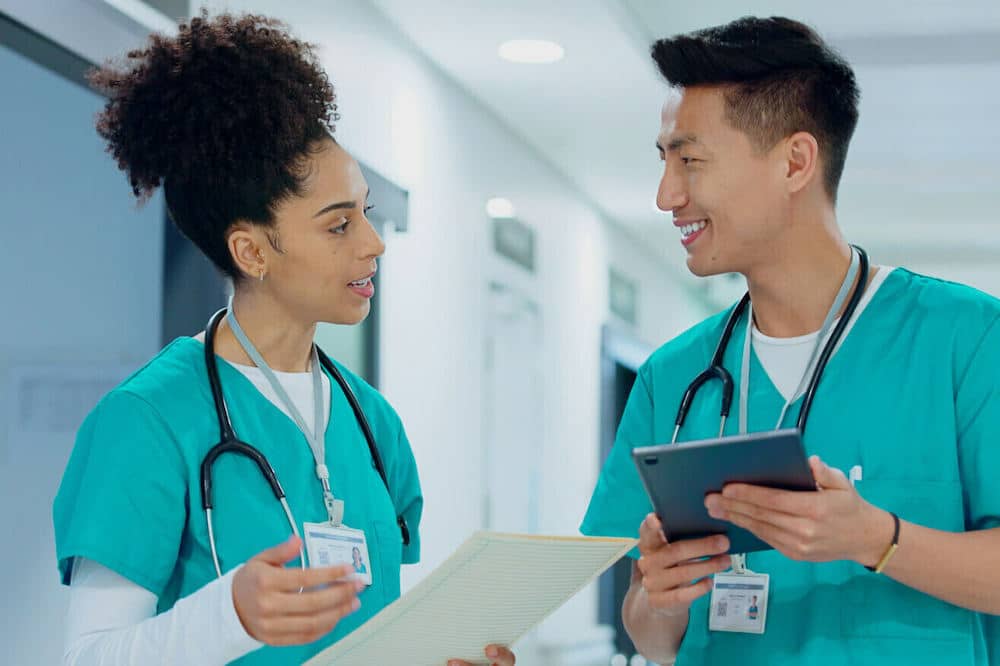 male nurse and female nurse talking to each other in the hallway of a hospital