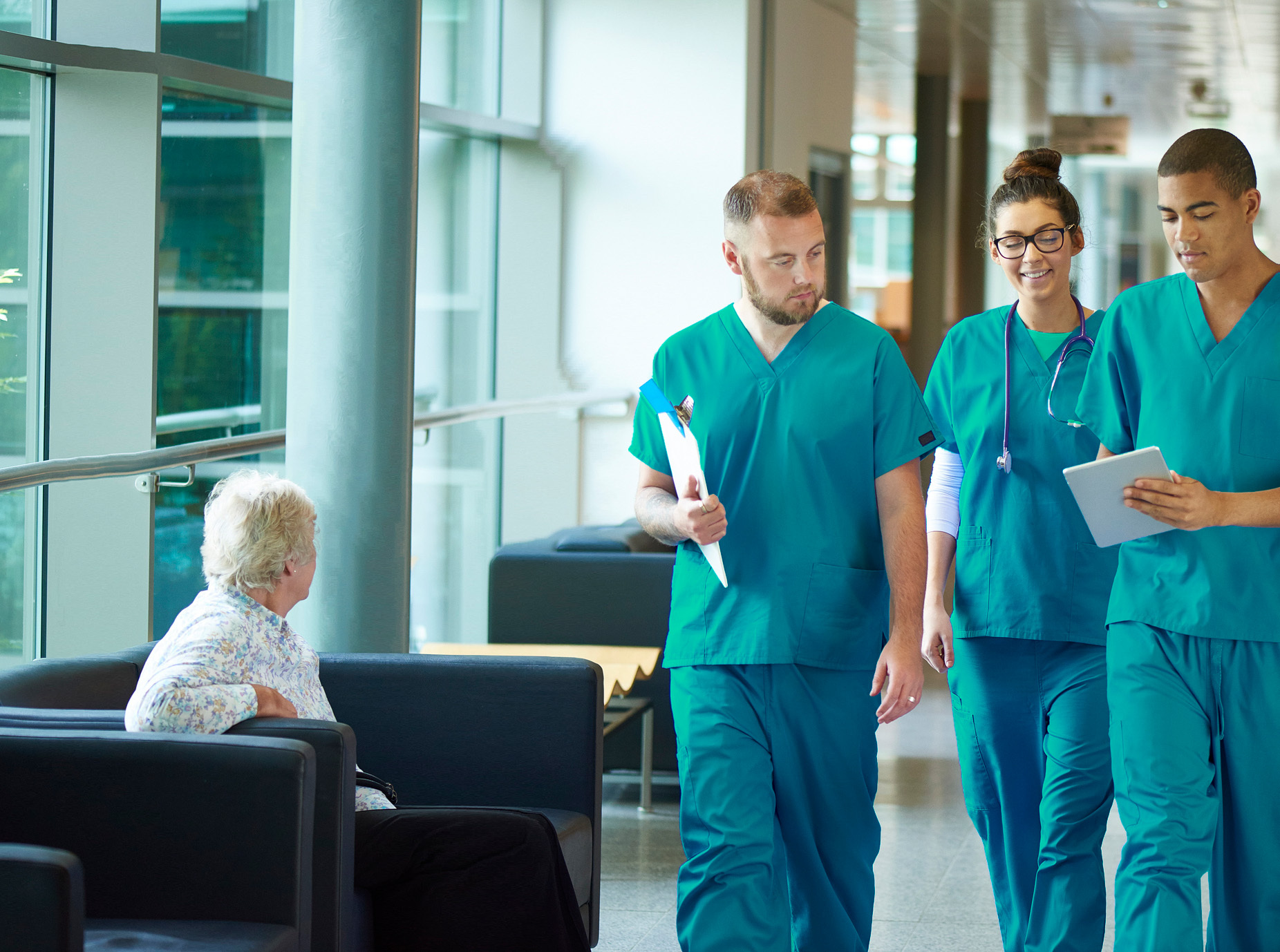 A diverse group of people walking together in a well-lit hallway, engaged in conversation.