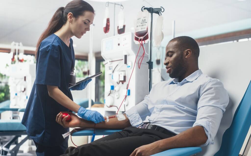 A nurse measures a man's blood pressure using a sphygmomanometer in a clinical setting.