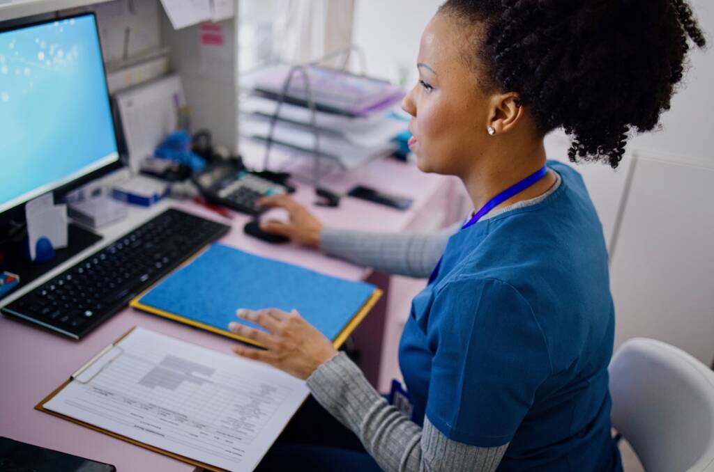 Woman using computer to work as nurse in the private clinic.