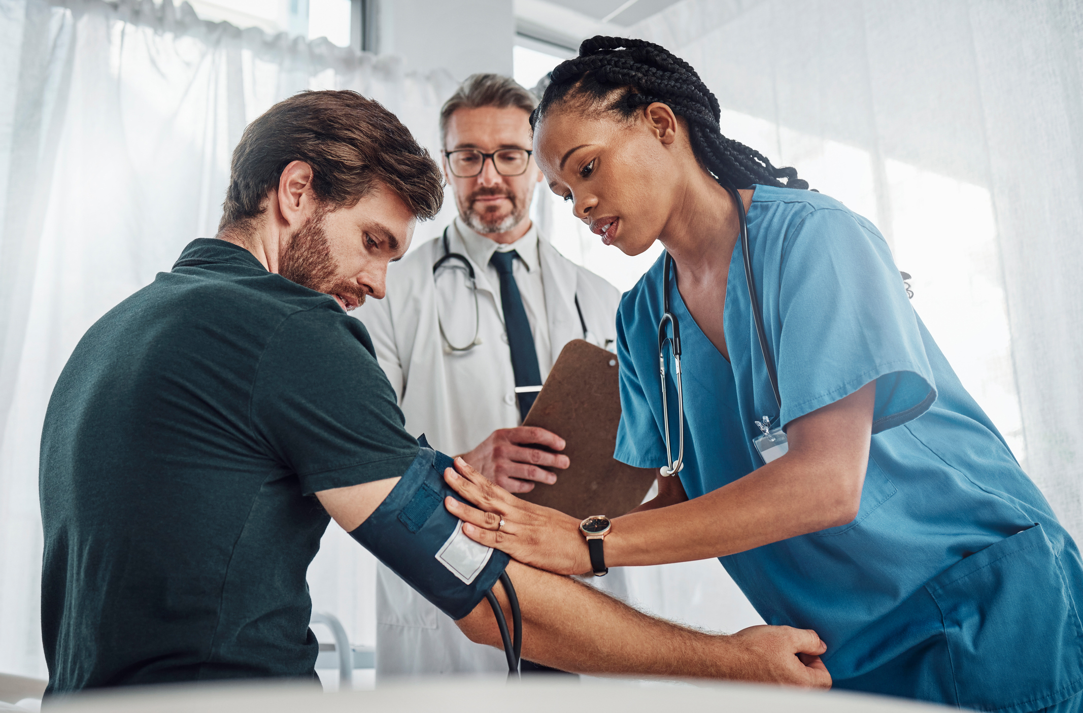 A healthcare professional checks a patient's blood pressure with a cuff and monitor in a doctor's office.